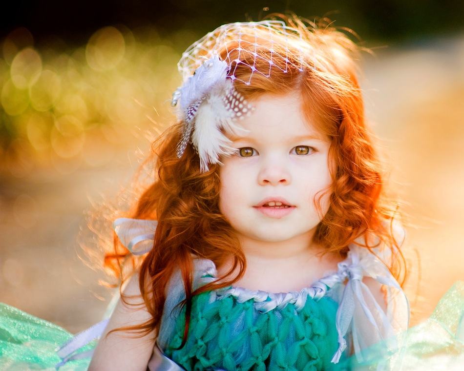 Redhead girl with amber eyes wearing green dress. 
